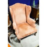 A Victorian upholstered wing back armchair, in the George II style,
