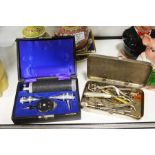 A tin of various medical instruments and a boxed O