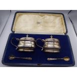 A cased pair of Richard Comyns silver salts with matching spoons and original blue glass liners,