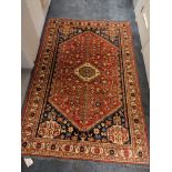 A Persian rug, central red medallion on a navy ground