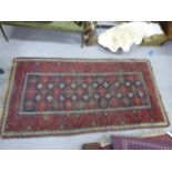 An Oriental rug with red and navy border, 105cm x 205cm
