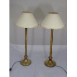 A pair of brass table lamps with cream colour shades,