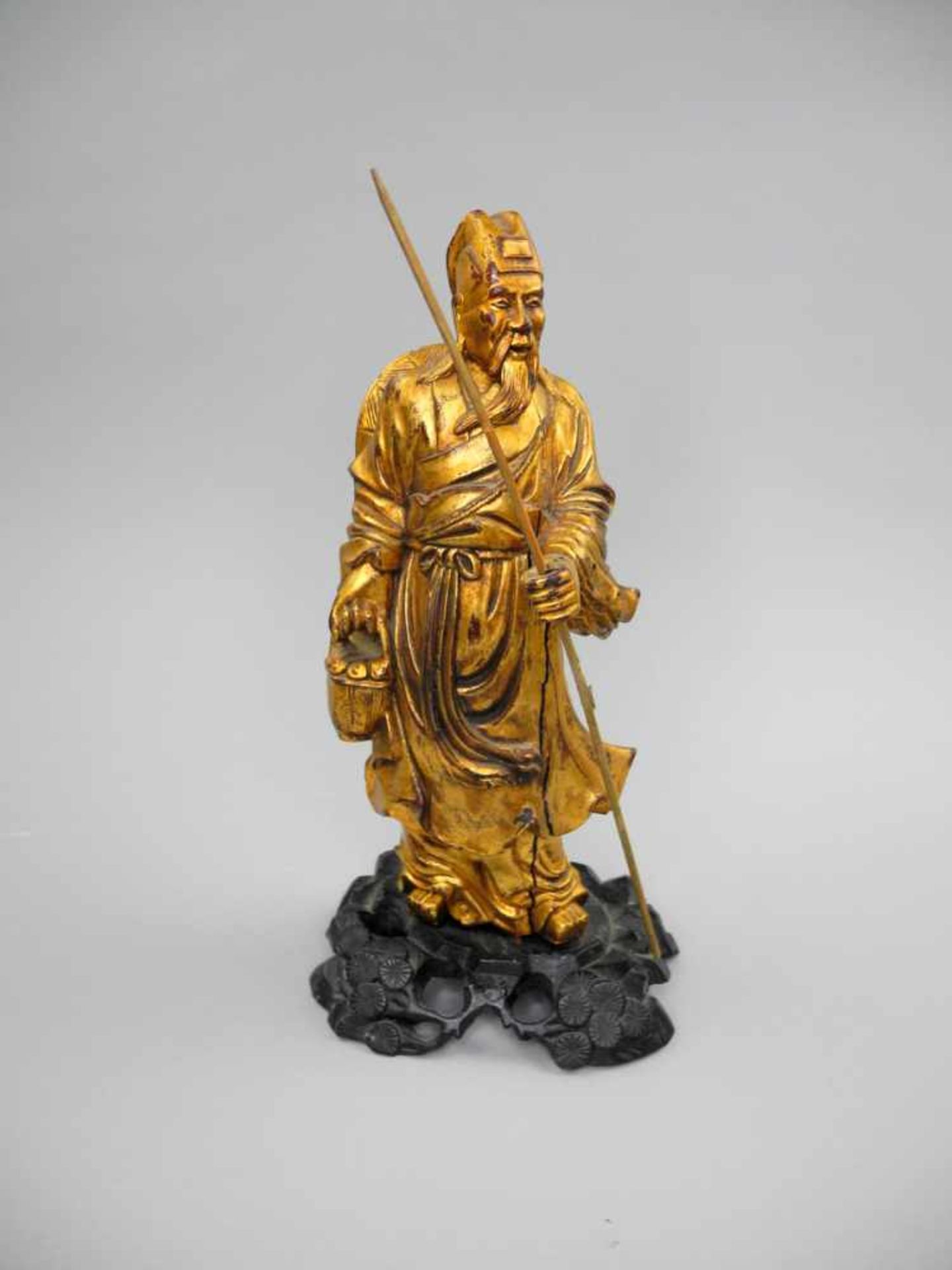 Chinesische HolzfigurHolz geschnitzt, goldfarben gefasst, auf dunkel lackiertem Holzsockel. Figur
