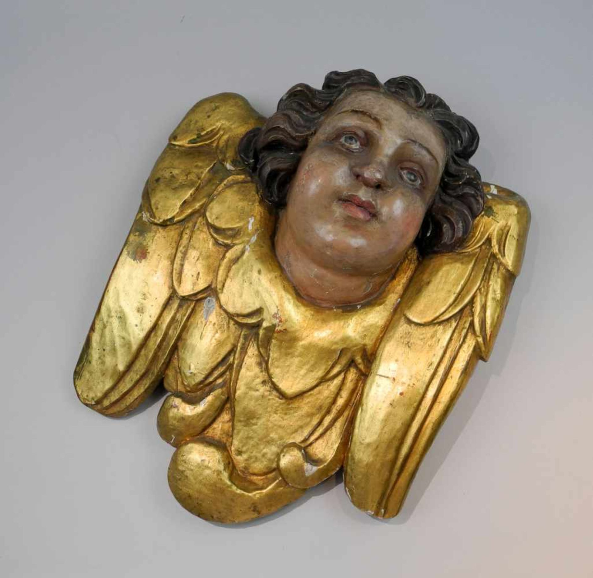 Engelkopf mit FlügelkragenHolz geschnitzt. Polychrom bemalter Kopf eines Engels mit goldfarbenem