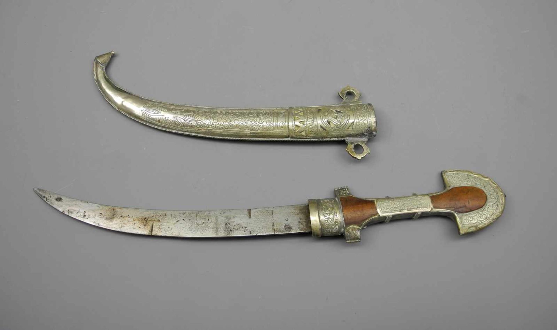 Arabischer Gewand-DolchGewand-Dolch mit gebogener Klinge und Holzgriff mit Metallbeschlägen.