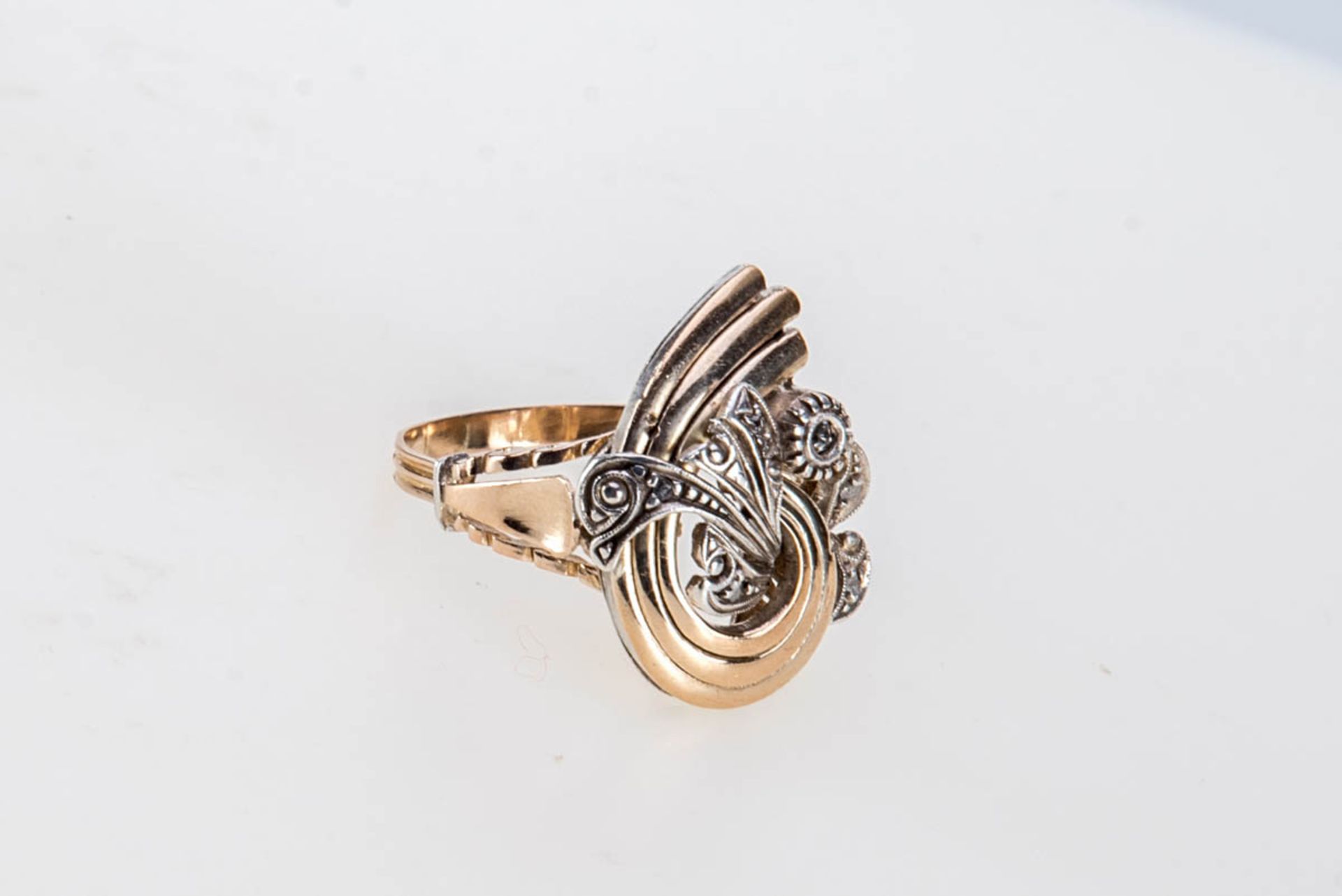 Ring mit Diamant585er Gelbgold, Weißgold. Glatte Ringschiene, knotenförmiger Ringkopf mit Blattmotiv