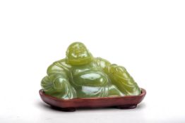 Glücksbuddha, ChinaApfelgrüne Jade, geschnitten. Auf Holzsockel lose aufgesetzte Figur des