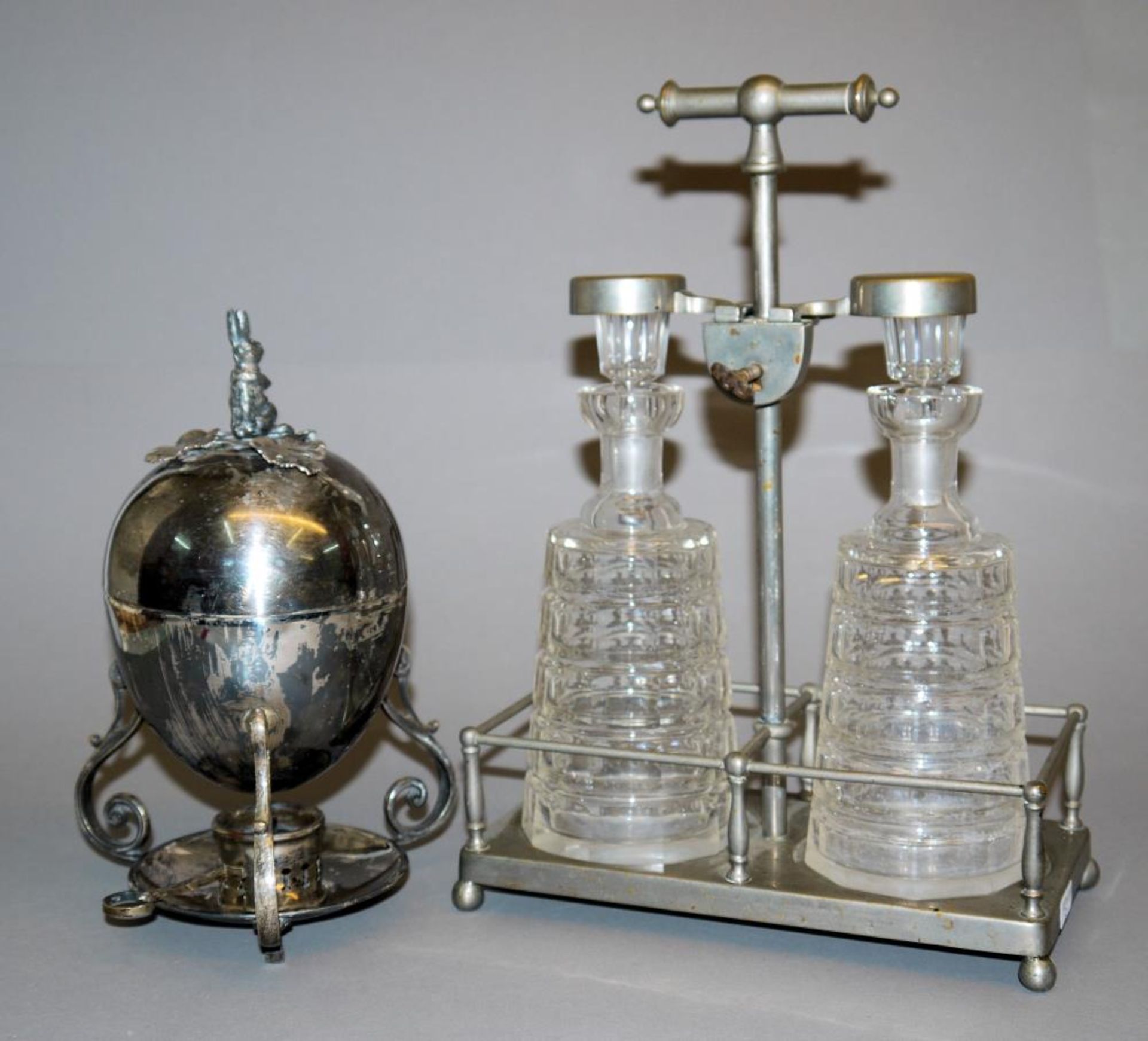Tantalus mit zwei Flaschen um 1920 & Eierkocher, versilbert Abschließbare Menage und Halterung für