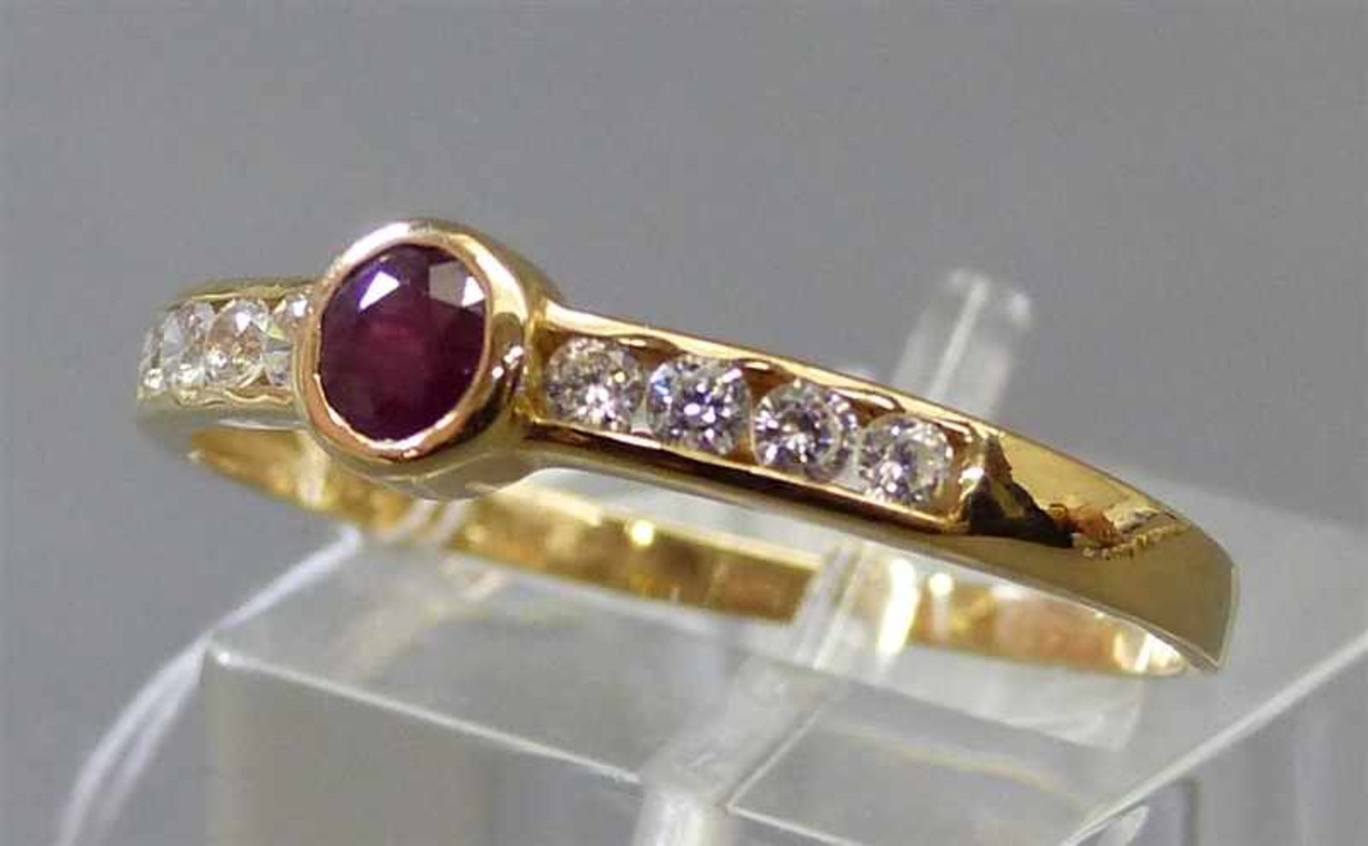 Damenring14 kt. Gelbgold, mittig 1 Rubin, 8 Kristallsteine als Besatz, ca 2g, RM 65,