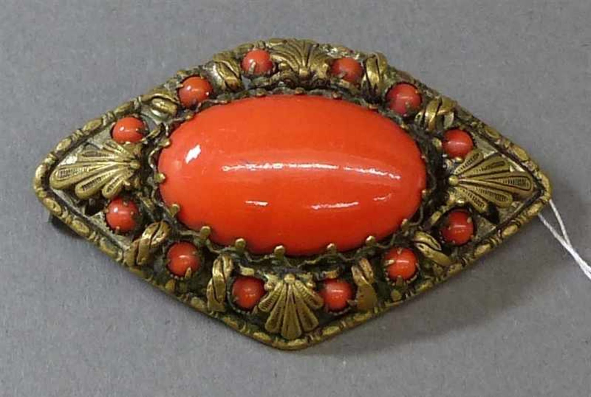 Brosche, um 1900Metallmontur, 1 ovaler Korallcabochon, 12 kleine Korallperlchen, l 5 cm,