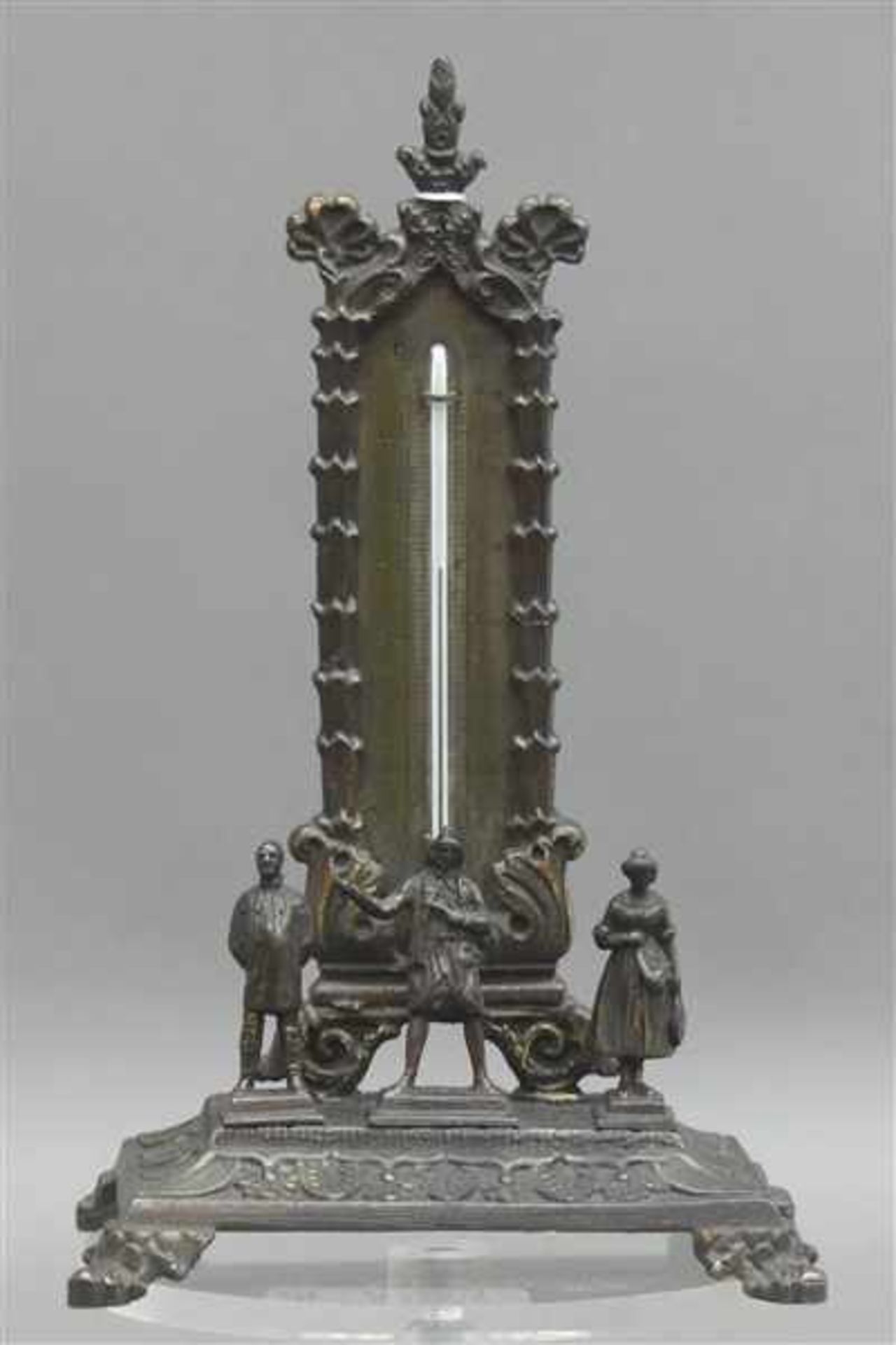 ThermometerMetall, bronziert, Reliefdekor, 3 kleine Figürchen, auf Sockel, h 16,5 cm,- - -20.00 %