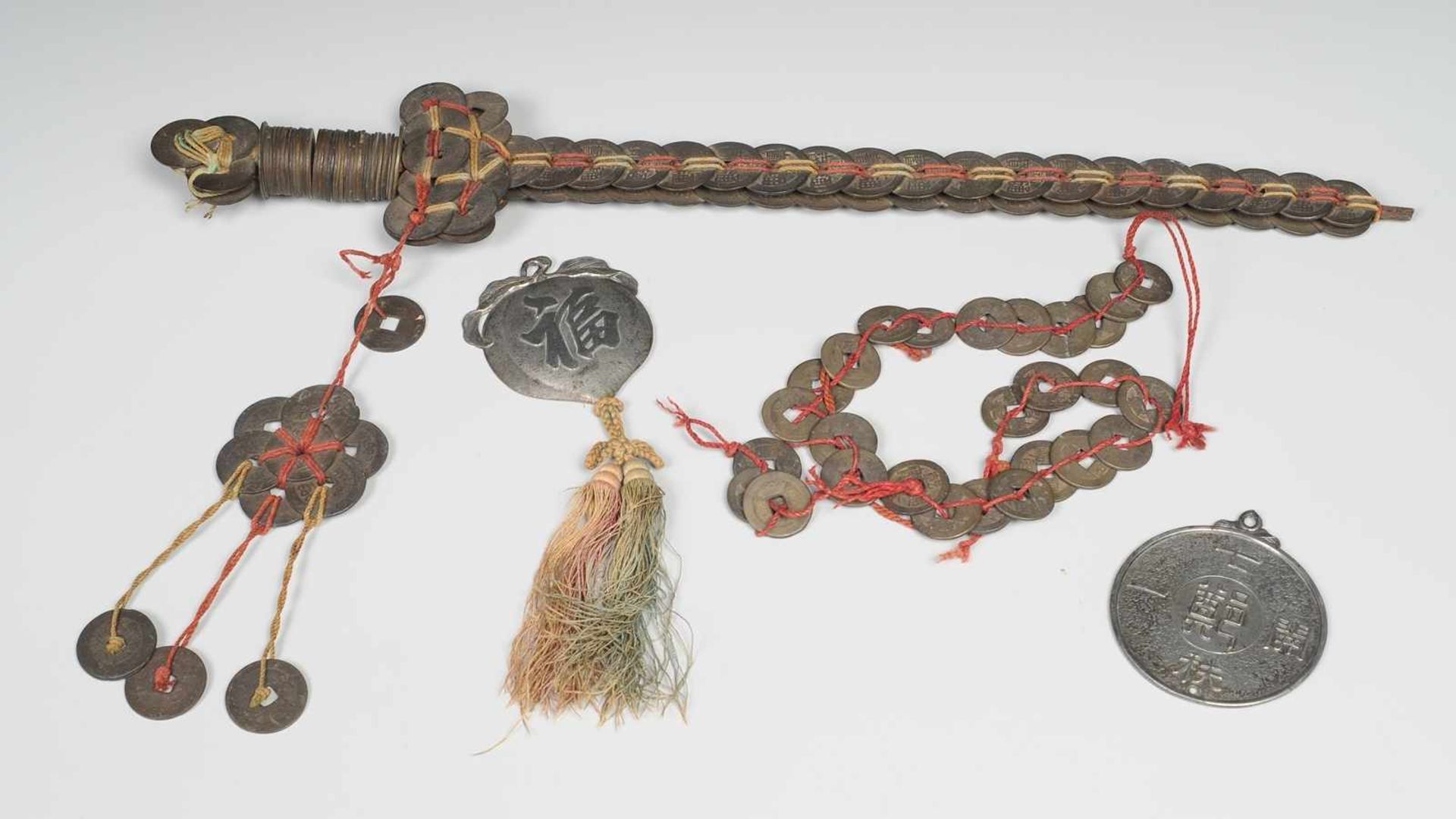 Käsch-Schwert mit Münzketten und AnhängernTalisman-Schwert aus auf Metallstange geknoteten Münzen