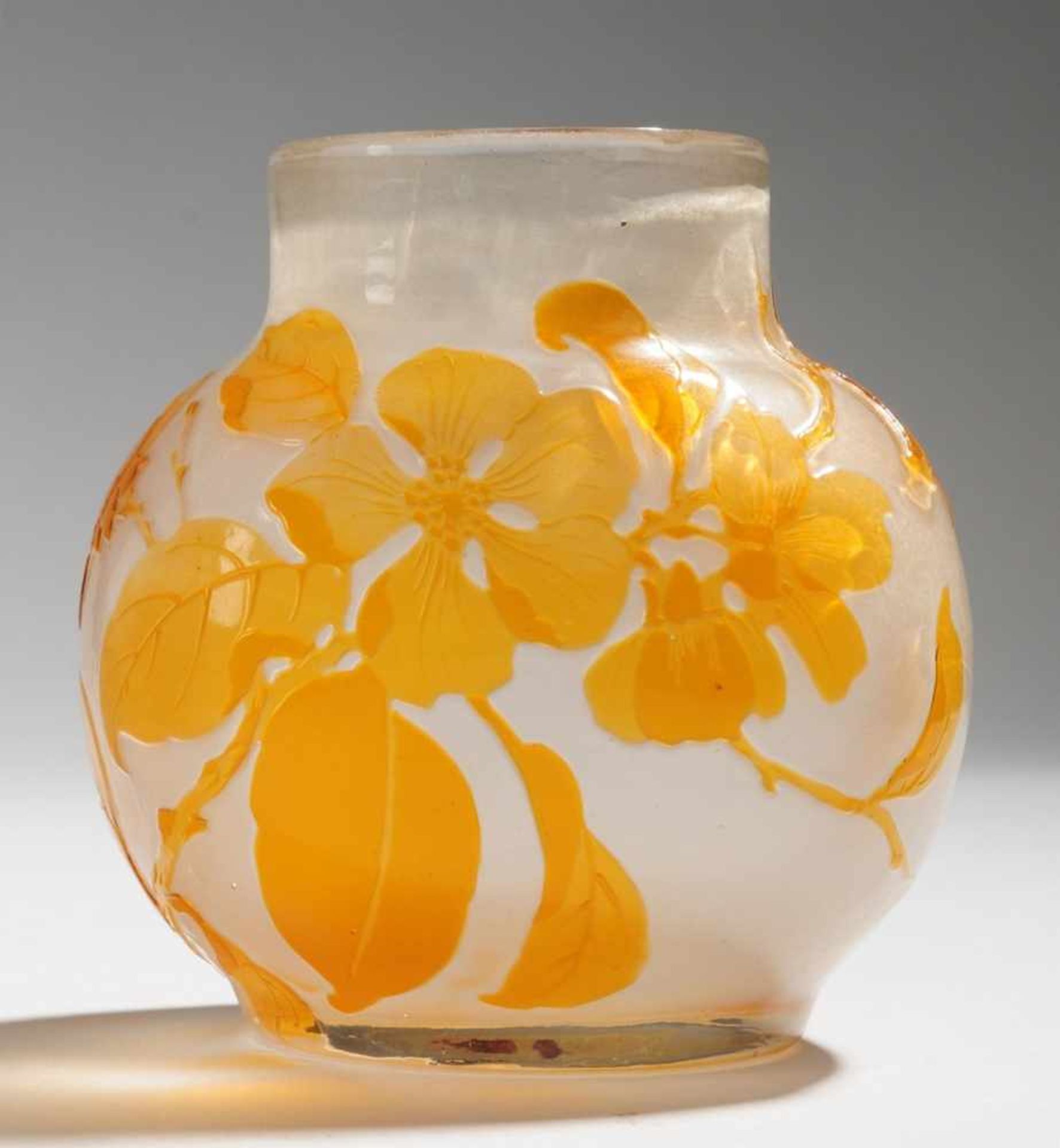 Kleine Vase mit ObstbaumblütenzweigFarbloses Glas, ockerfarben überfangen. Formgeblasen,