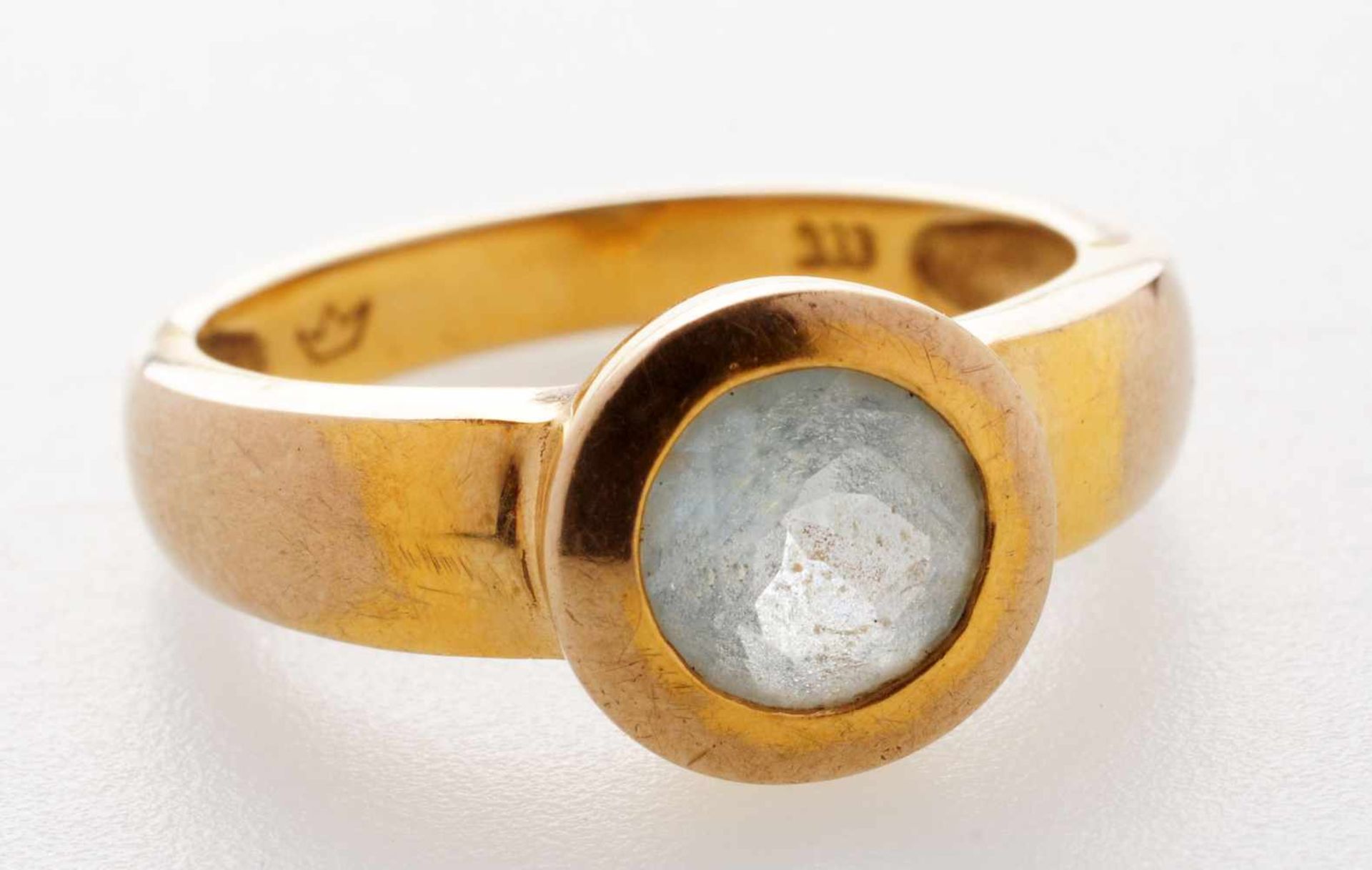 Ring mit hellblauem Stein333er GG. Flache, an der Schulter verbreiterte u. gewölbte Ringschiene.