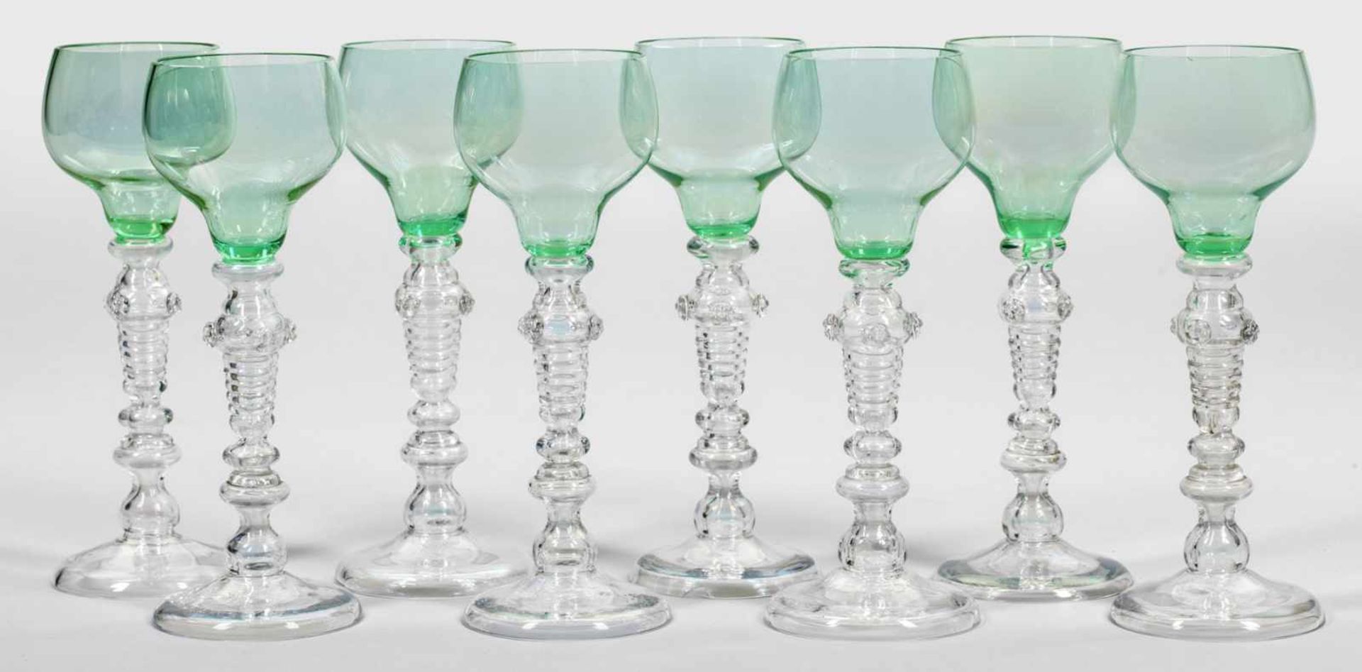 Acht Historismus-RömerFarbloses Glas, die Kuppa aus zart grünlichem Glas. Auf gewölbtem Fuß reich