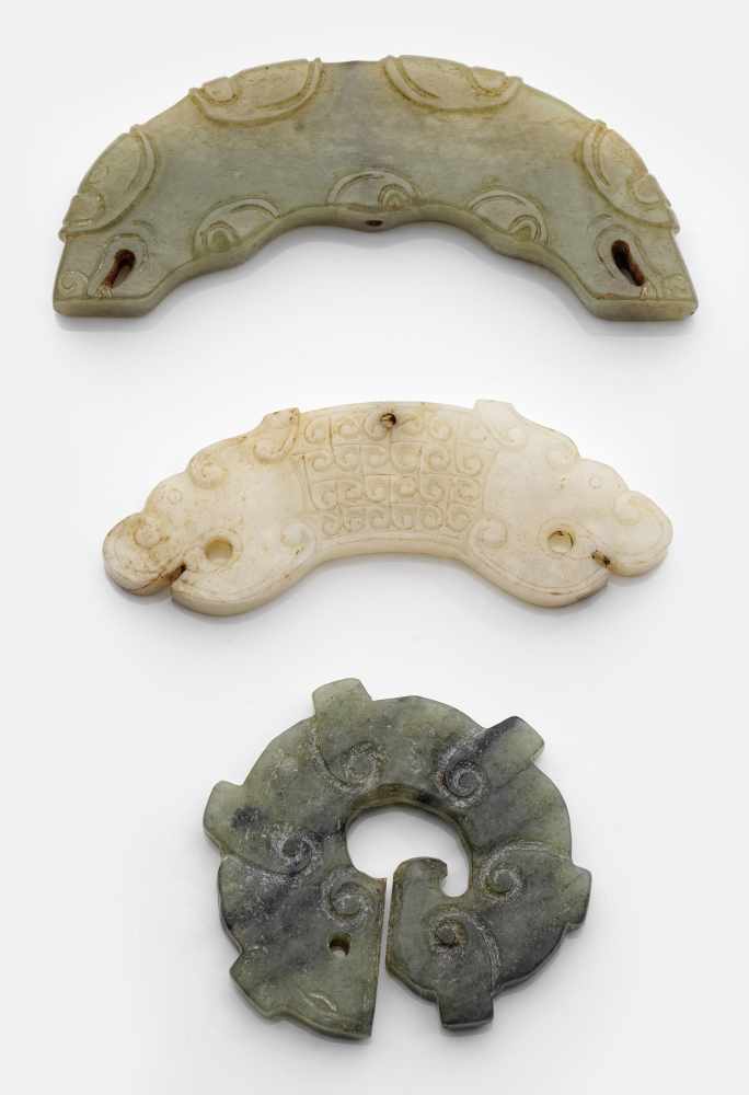 Drei Drachen-Anhänger im archaischen StilSeladongrüne, gewölkte und geäderte sowie Hammelfettjade.