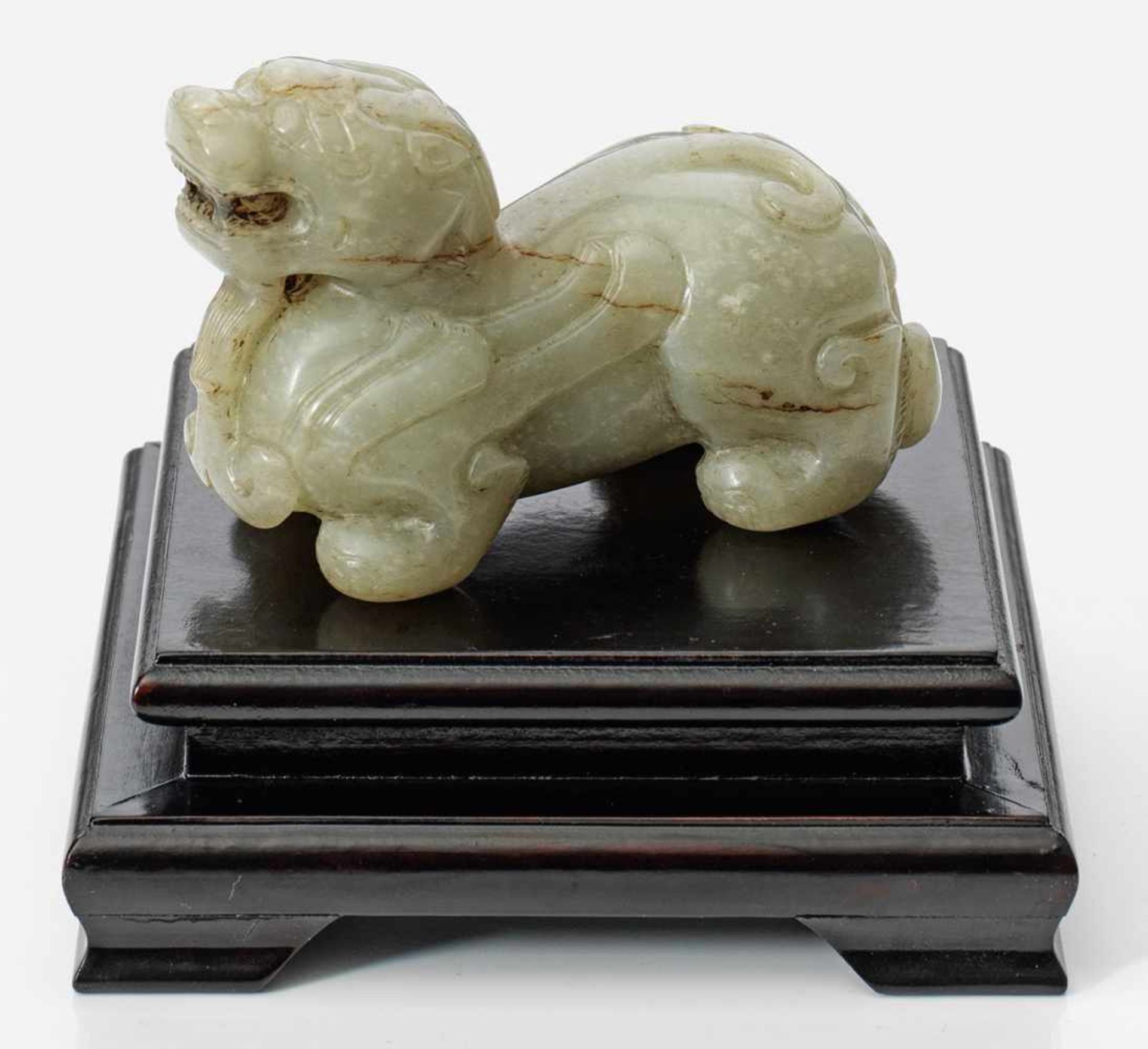 Jade-Figur eines Fo-Hundes im archaischen StilHelle, seladongrüne Jade mit rostbraunen Einschlüssen,