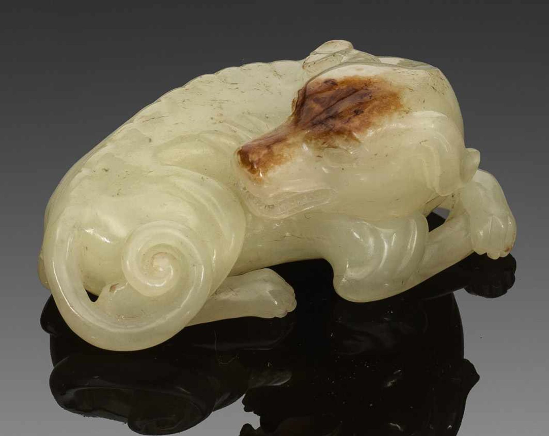 Jade-Figur eines HundesHelle, seladongrüne Hetian-Jade mit rostbraunen Einschlüssen, fein geschnitzt