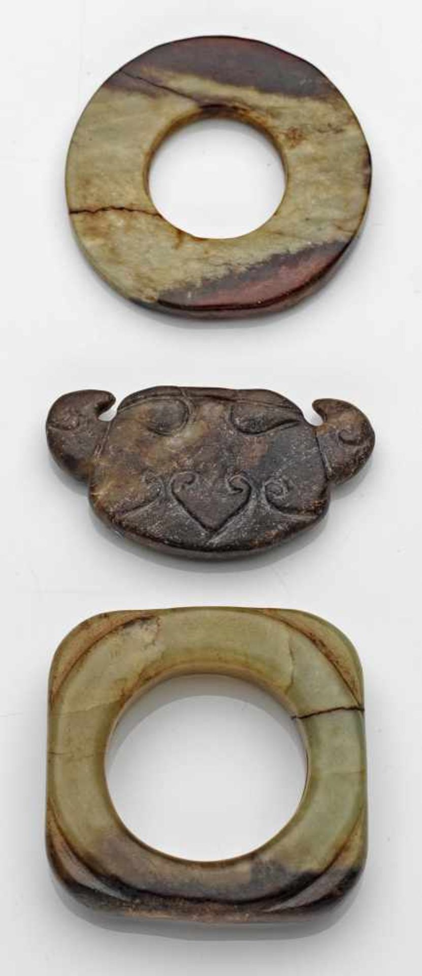 Drei JadeschnitzereienSeladongrün-gelbliche bis rostbraune Nephrit-Jade, geschnitzt. D. 4,5 cm. 2,