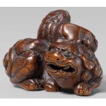 A wood netsuke of a shishi with young. Late 18th/early 19th centuryThe parent recumbent, snarling