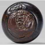 A rare wooden kagamibuta. 19th centuryThe circular domed disc carved in relief with Hotei sitting in