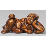 A boxwood netsuke of a sleeping sarumawashi. 18th/early 19th centuryLying asleep with a smile, his