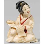 A Tokyo school ivory shunga netsuke of a young woman with a scroll, by Hakuunsai II. Late 19th