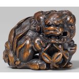 A fine boxwood netsuke of a shishi and young. Mid 19th centurySeated on its hind legs, head