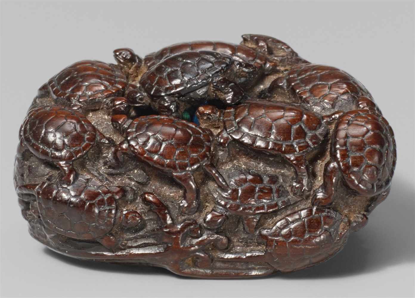 A reddish-brown wood netsuke of a group of fifteen tortoises, by Yôzan. Early 19th centuryPartly