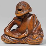 A boxwood netsuke of a professional sneezer, by Gyokkei. Mid-19th centurySeated cross-legged,