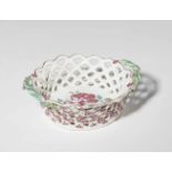A faience basket with rose decorRound, pierced basket with floral appliques and tendril handles.
