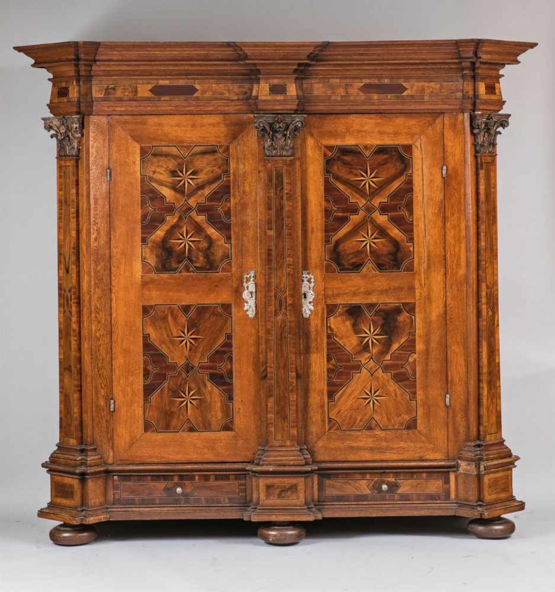 A German pilaster cabinetWalnut, oak, plum, maple, and ebonised wood veneer on softwood, cast iron