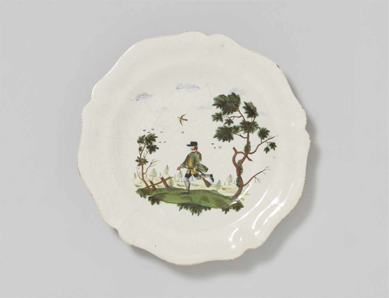 A faience plate with a hunting motifOf scalloped form with finely painted decor. Unmarked. D 24.2