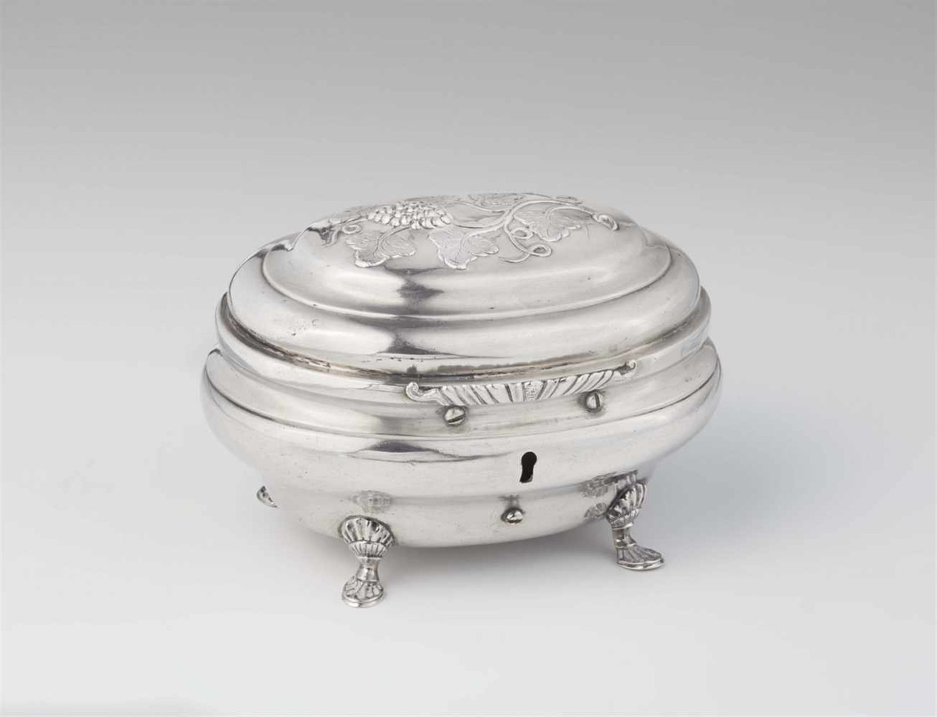 A Naumburg silver sugar boxBombé form box on four shell supports, the hinged lid with grapevine