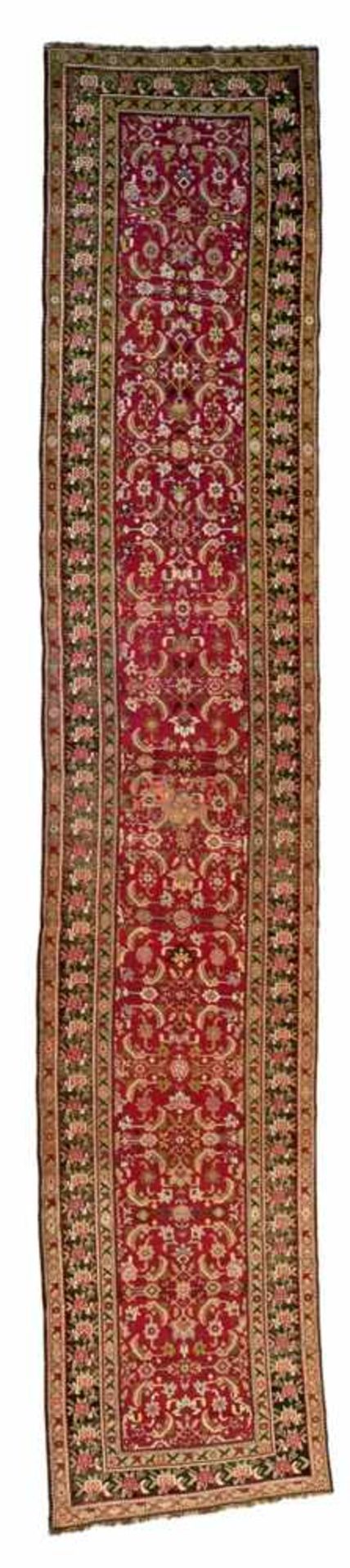 An Iranian hallway runnerWool. With herati decor on cherry red ground and floral borders on black.