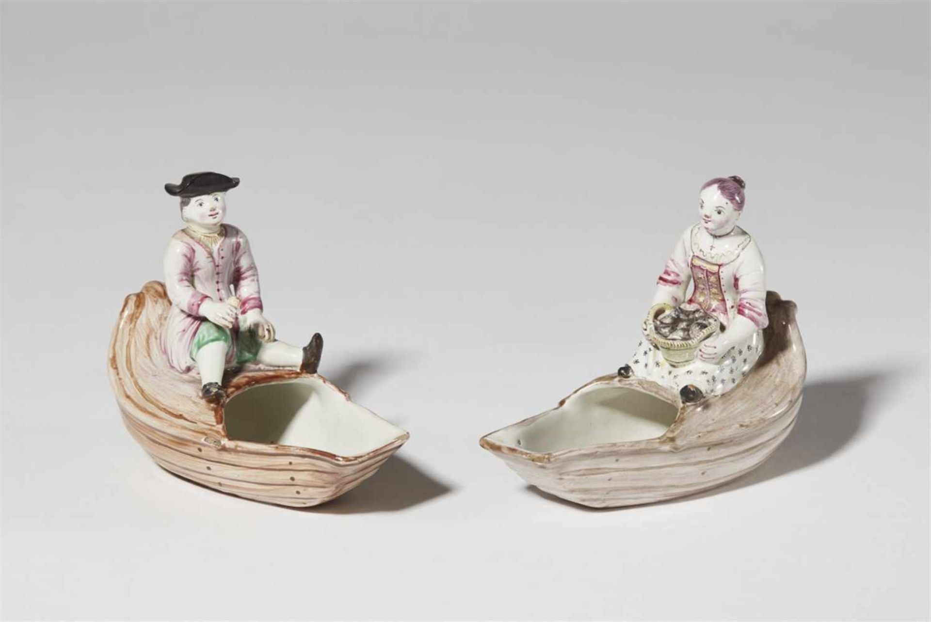 A pair of Strasbourg faience condiment dishes with figuresA rustic gentleman and a lady seated on