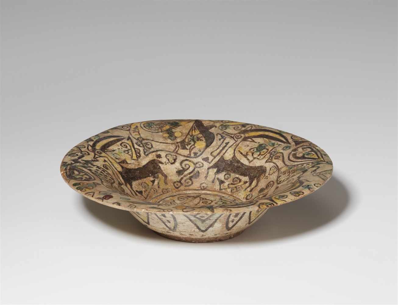 An East Iranian fritware dish with peacocks and ibexesQuarz frit with yellow, dark purple, and green - Image 2 of 2
