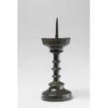 A Gothic tin candlestickWith iron pricket. The drip pan slightly dented, a later breakage to the