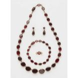 A 14k red gold and garnet demi-parureComprising a necklace and bracelet with graduated oval