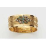 An 18k gold and emerald bangleHinged extendable bangle with relief decor and a silver applique set