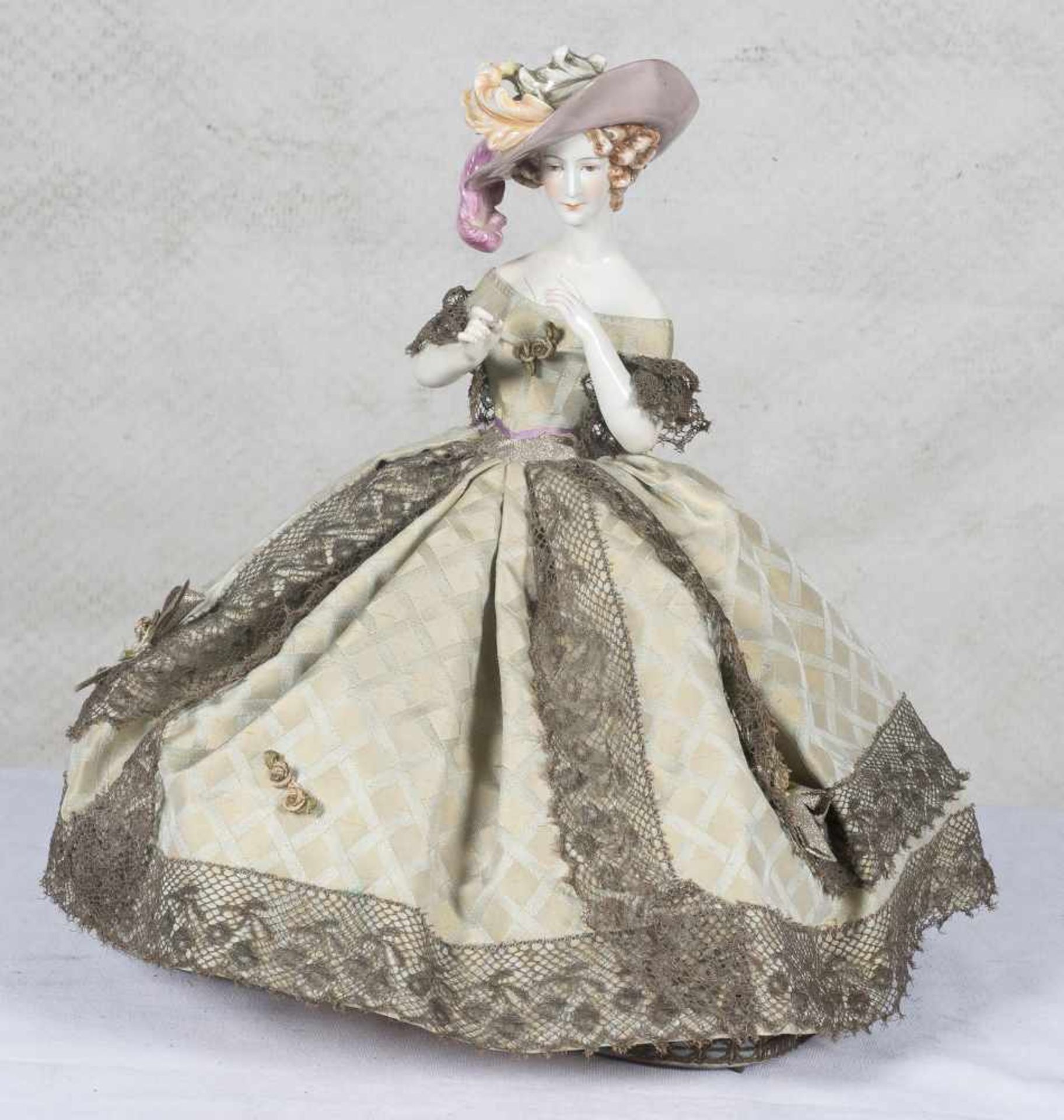 Polychromed porcelain doll wearing a knitwear and silk dress with a sewing kit hidden inside it. Art