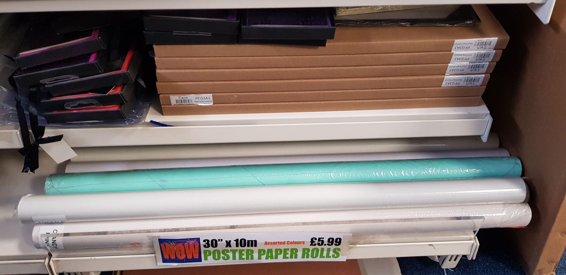 Two shelves with 14 rolls of poster paper and 6 A3 size snap frames & notelets