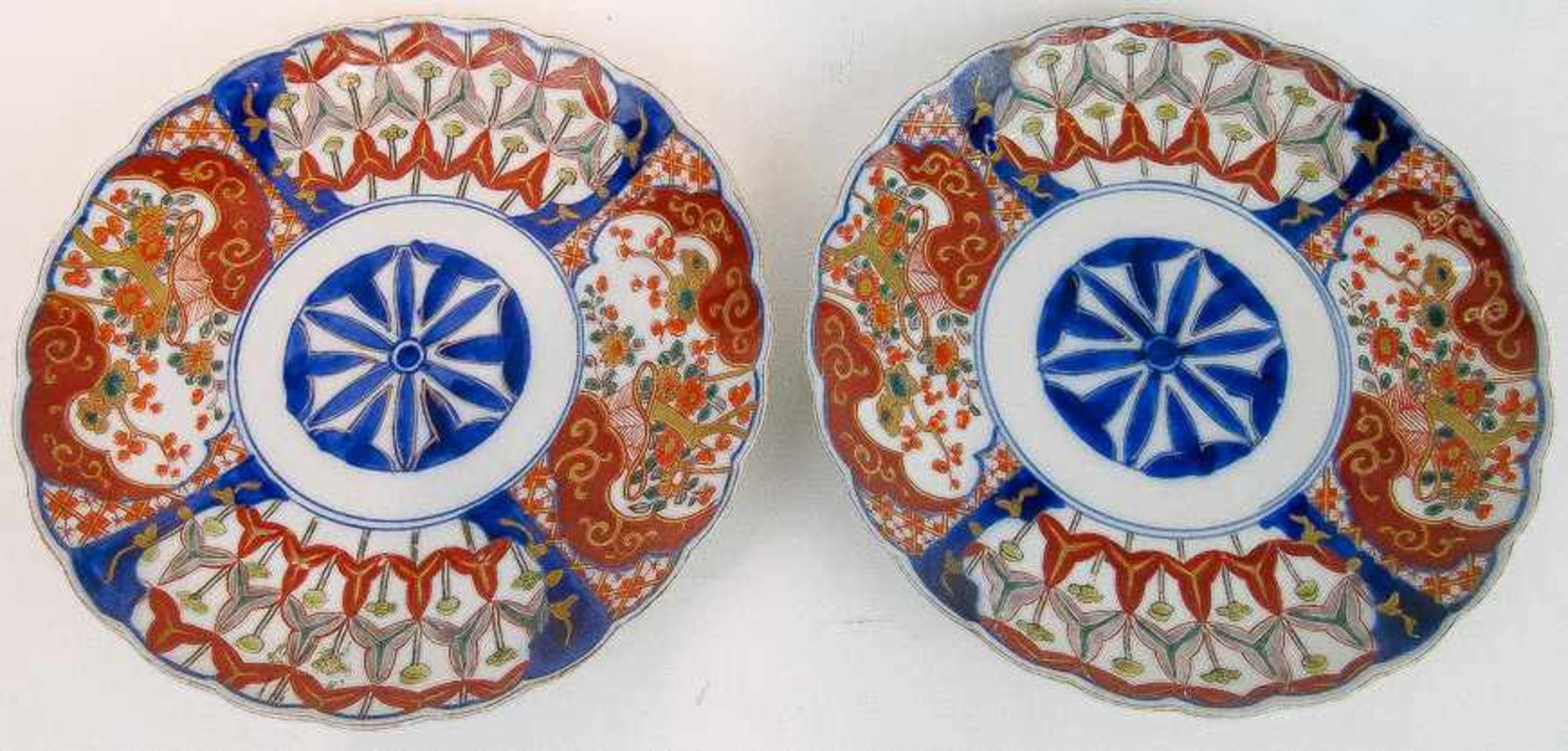 Ein Paar Teller mit gewelltem RandJapan, ImariPorzellan. Um stilisierte Mittelblüte verschiedene