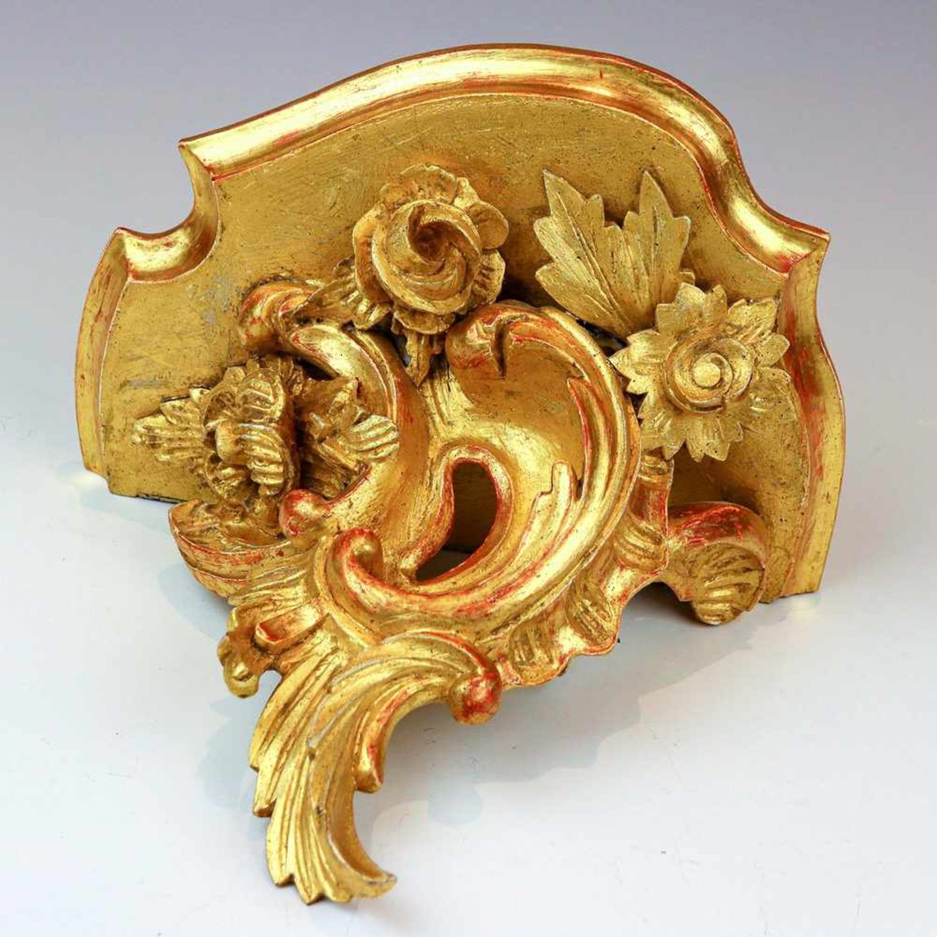 KonsoleGeschweifte Holzplatte auf Rocaille mit Blumenschmuck. Holz, gold gefasst. 24×28,5×20 cm.(