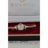 In its original box, ladies 9ct cased wristwatch by Bulova on a 9ct bracelet, total weight 15.9g