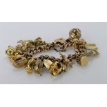 9ct / yellow metal charm bracelet with a good selection of charms attached, total weight 63.2g