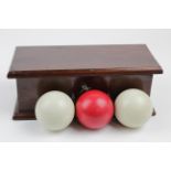 Billiards interest. Set of three billiard balls, contained in a stained oak case