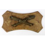 Vickers Machine Gun:- cast crossed guns on small wooden plaque, this hung in one of the factory