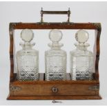 Oak tantalus, containing three cut glass decanters, key present however lock not working, height