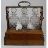 Oak three decanter tantalus, with brass mounts & sectionalised drawer beneath, patent stamp to brass